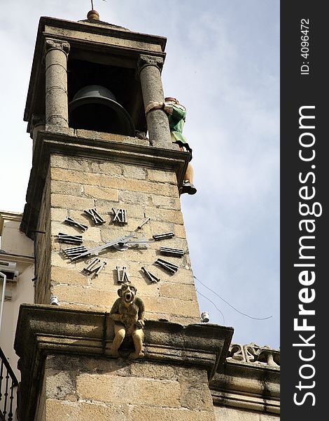 Spanish bell tower with a statue screaming and a puppet hitting bell. Spanish bell tower with a statue screaming and a puppet hitting bell