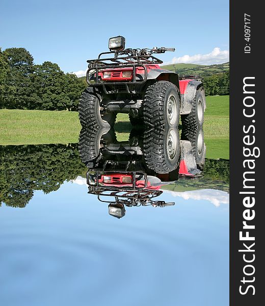 Red and black four wheel drive quad bike, with reflection in rippled water, standing on the grass and partially submerged in the water. Rural countryside and a blue sky to the rear. Red and black four wheel drive quad bike, with reflection in rippled water, standing on the grass and partially submerged in the water. Rural countryside and a blue sky to the rear.