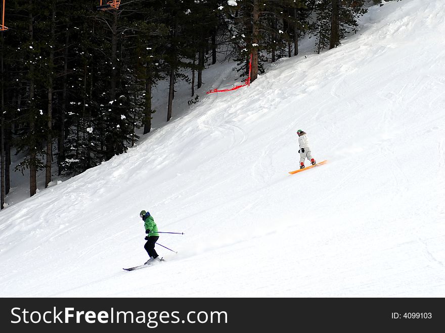 Two persons going downhill on a snowy slope. Two persons going downhill on a snowy slope