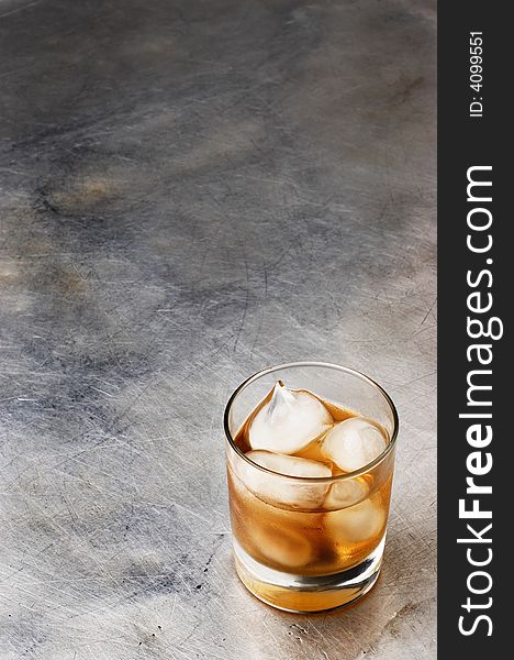 One shot of whiskey on the rocks, over metallic scratched surface. lot of copyspace .