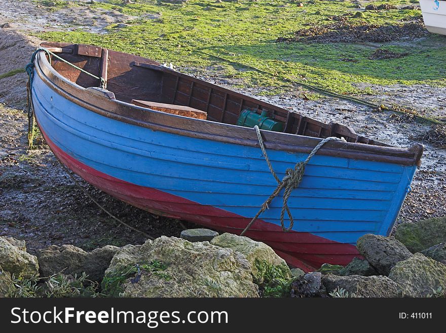 Blue & red wooden rowing boat on land. Blue & red wooden rowing boat on land