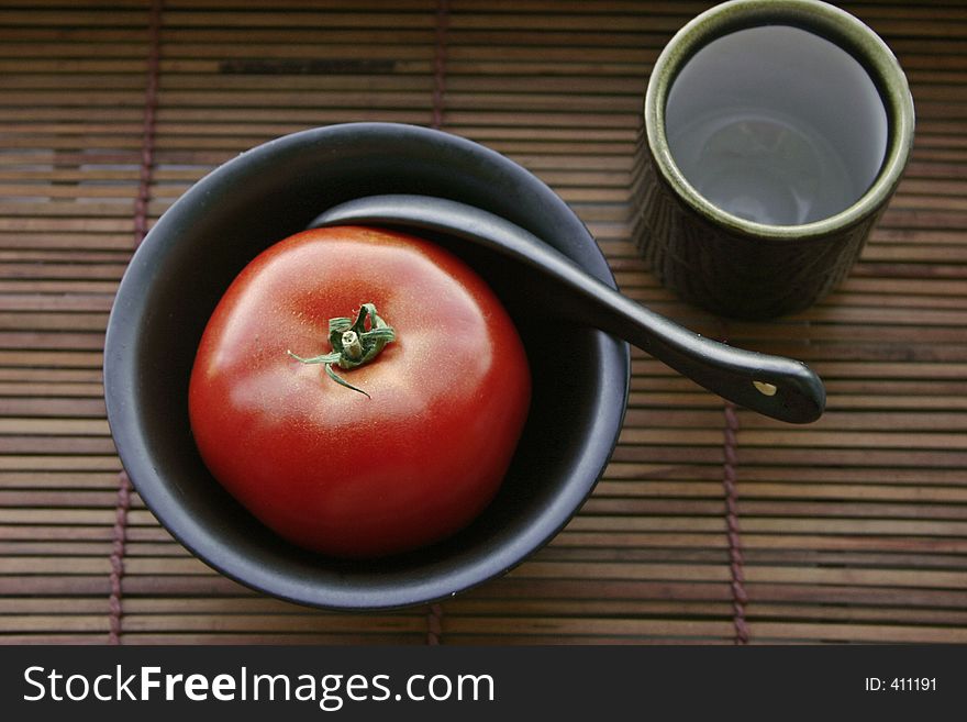 Tomato in a black bowl and a japanese teacup. Tomato in a black bowl and a japanese teacup