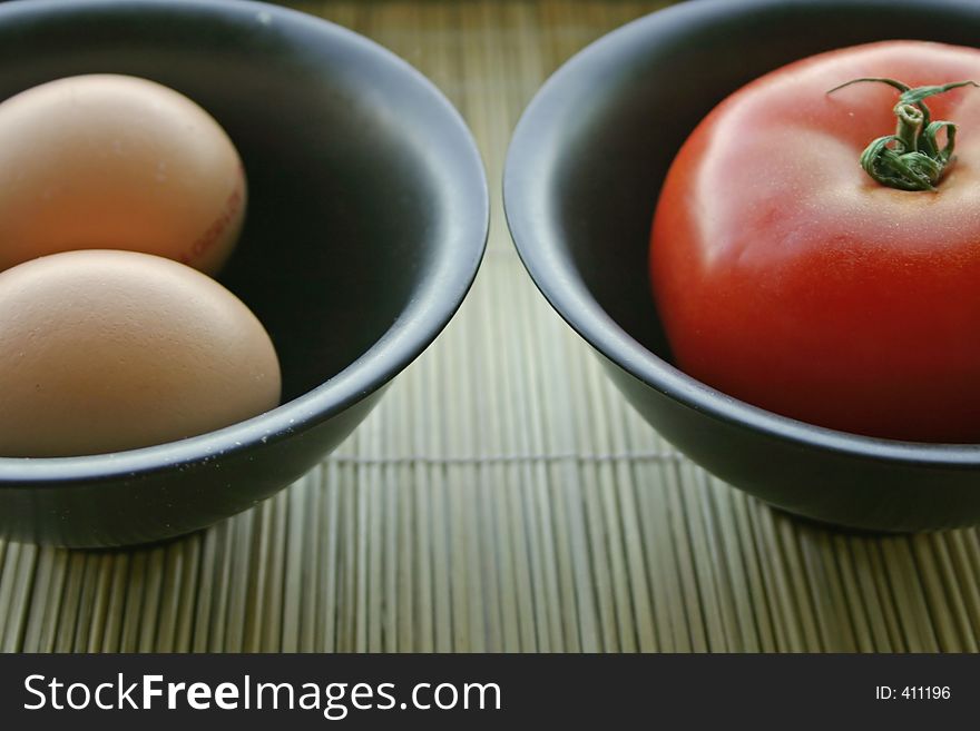 Eggs and tomatoes in black bowls. Eggs and tomatoes in black bowls