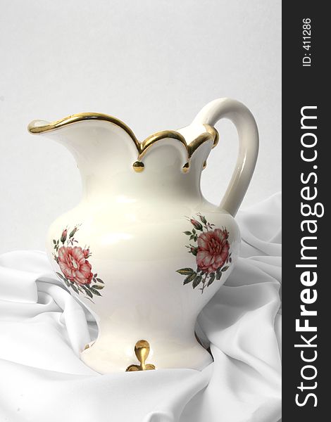 Ceramic water pitcher with gold trim on silky cloth