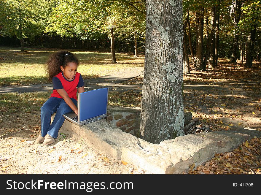 Seven year old child outside with laptop computer.