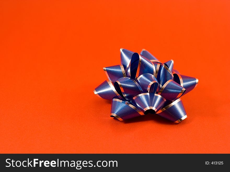 A blue gift bow isolated on a red backdrop.