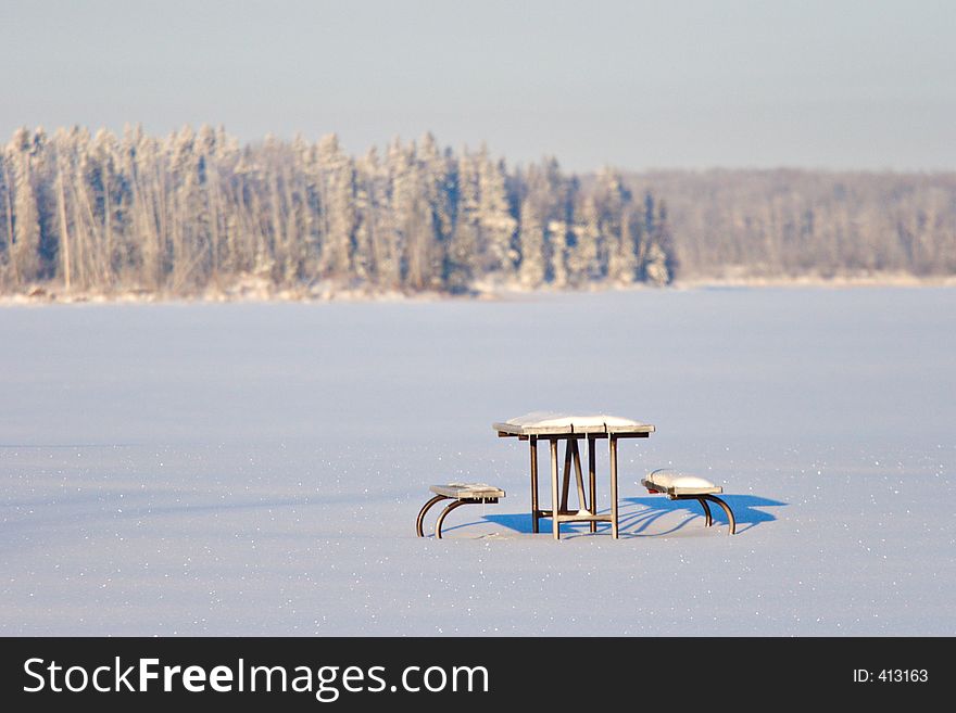 A snow covered picnic table waits for spring. A snow covered picnic table waits for spring.