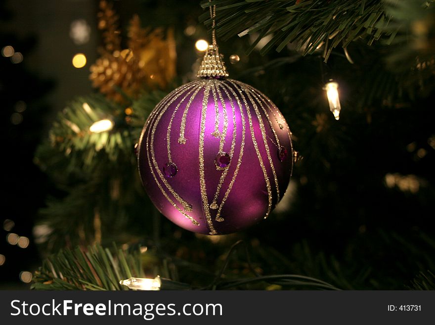 Elegant purple ornament (decorated with glitter and gems) on Christmas tree, surrounded by lights. Elegant purple ornament (decorated with glitter and gems) on Christmas tree, surrounded by lights.