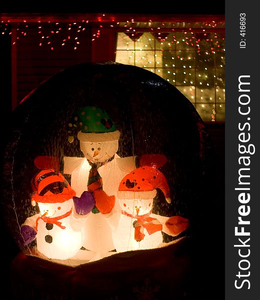 Three snowmen in a glass globe adorn a front lawn at Christmas. Three snowmen in a glass globe adorn a front lawn at Christmas.