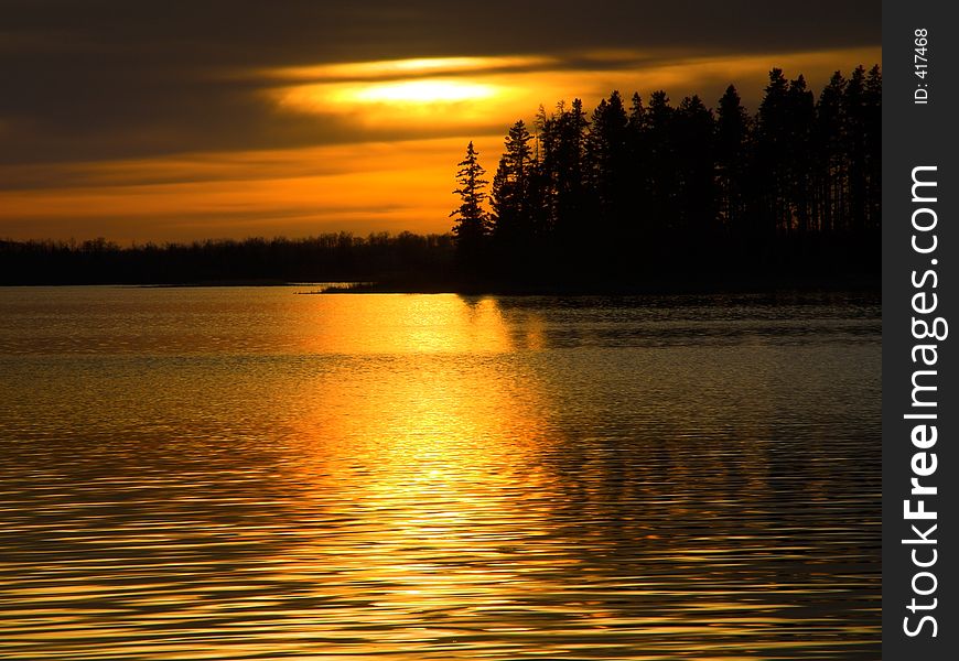 A golden sunset on a peaceful lake. A golden sunset on a peaceful lake.