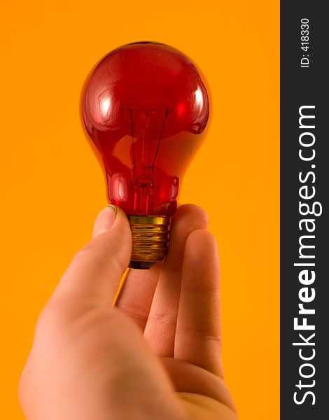 A red bulb held up against an orange background.