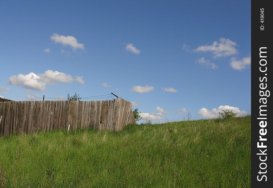 Idyllic view of a farm fence and a blue sky with a few clouds