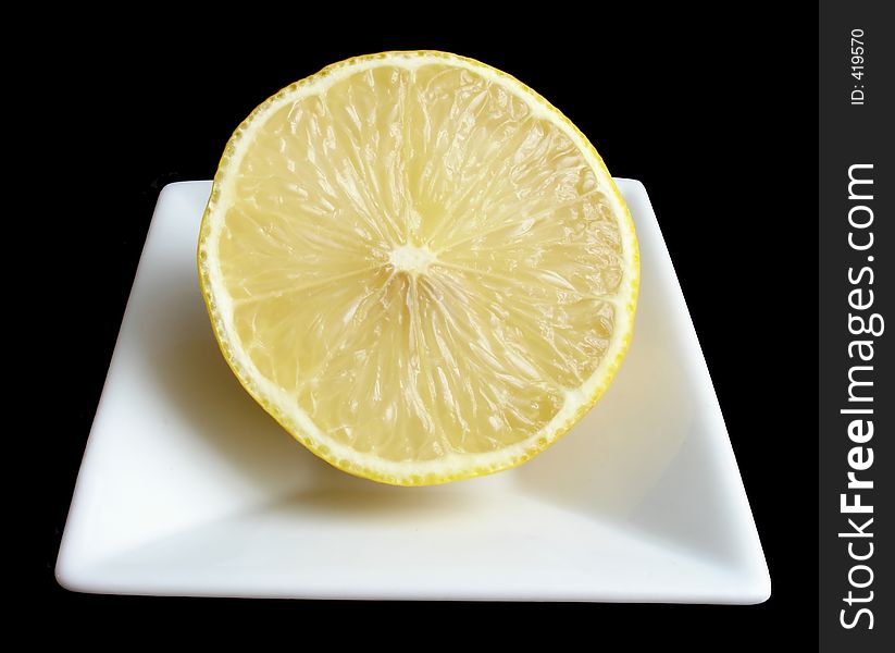 Half a lemon on a white mini dish, black background