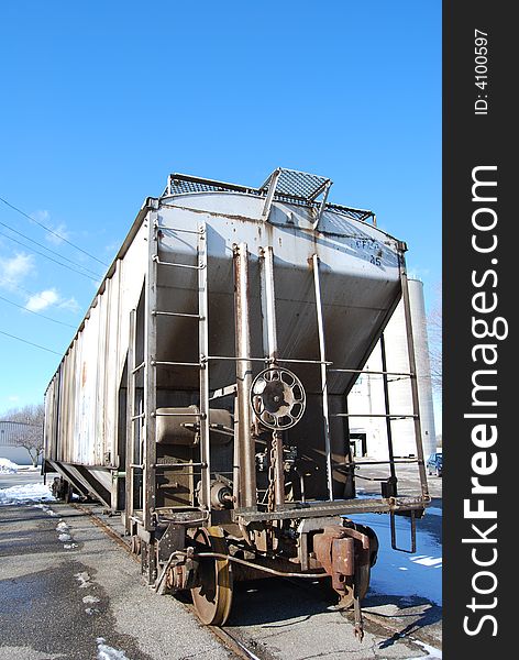 A train car parked on a siding on a bright blue sunny, but cold winter day.