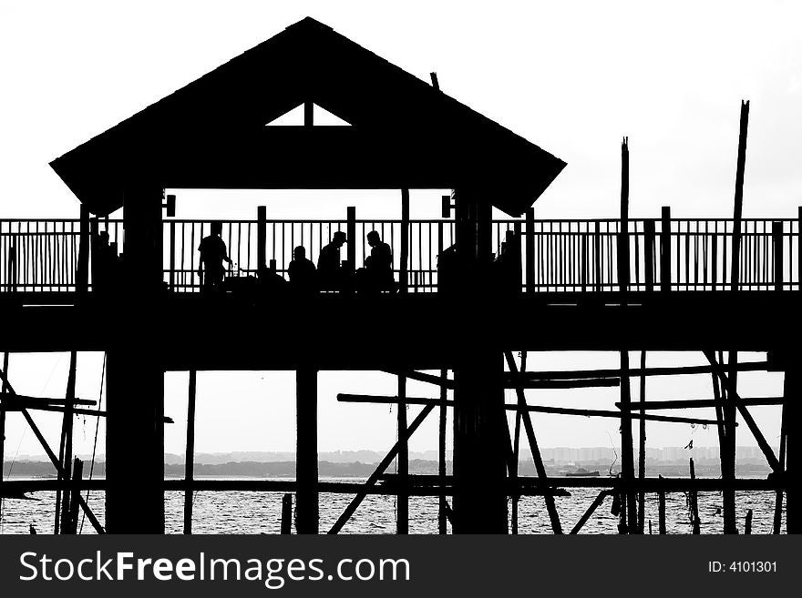 A silhouette outline of a shelter built along the shoreline. A silhouette outline of a shelter built along the shoreline