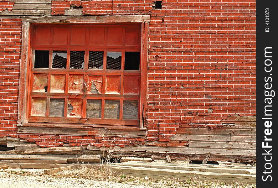 Red wall and loading dock door with broken windows, rotting wood and sagging timbers. Red wall and loading dock door with broken windows, rotting wood and sagging timbers