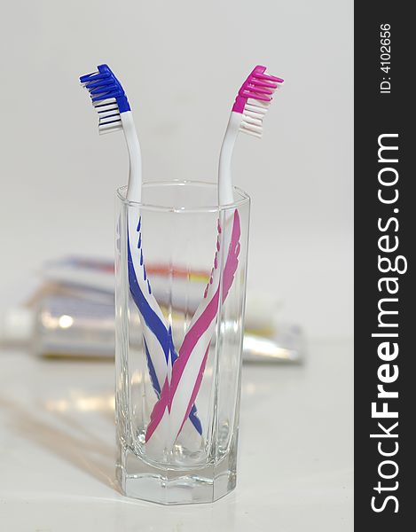 Two toothbrushes in the glass container against the bright background. Two toothbrushes in the glass container against the bright background.
