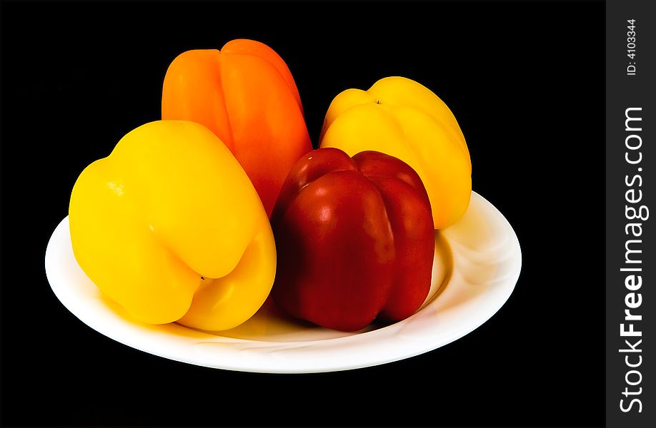 Capsicum in various colors, on white plate, black background. Capsicum in various colors, on white plate, black background