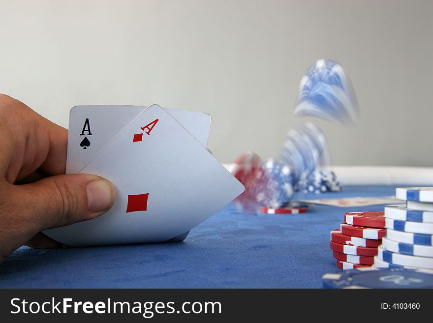A poker player holds two aces and throws chips onto the table to place a bet. A poker player holds two aces and throws chips onto the table to place a bet