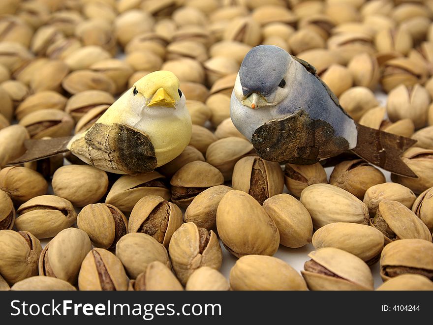 Two birds cork on background pistachios. Two birds cork on background pistachios