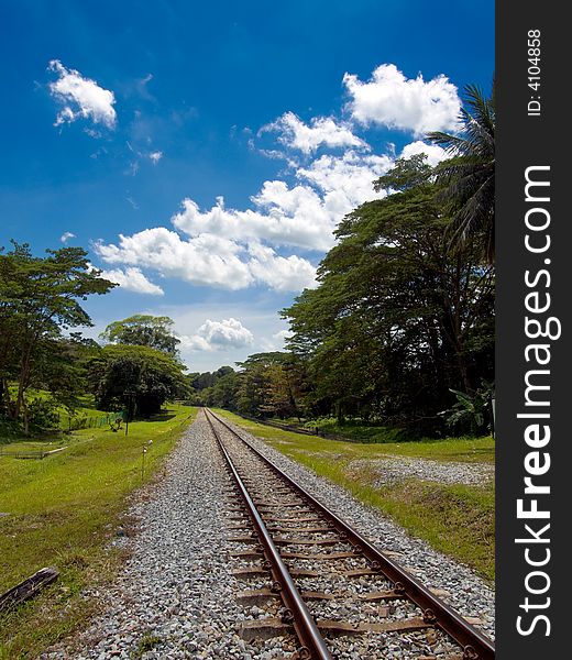 Railway track disappearing into the distance in a partly cloudy sky