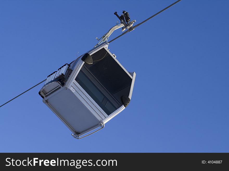 Gondola ski lift on cable with clear sky background. Gondola ski lift on cable with clear sky background