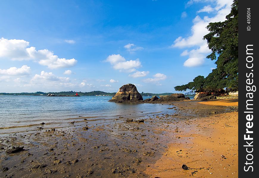 Muddy beach at low tide in a bright later afternoon sky