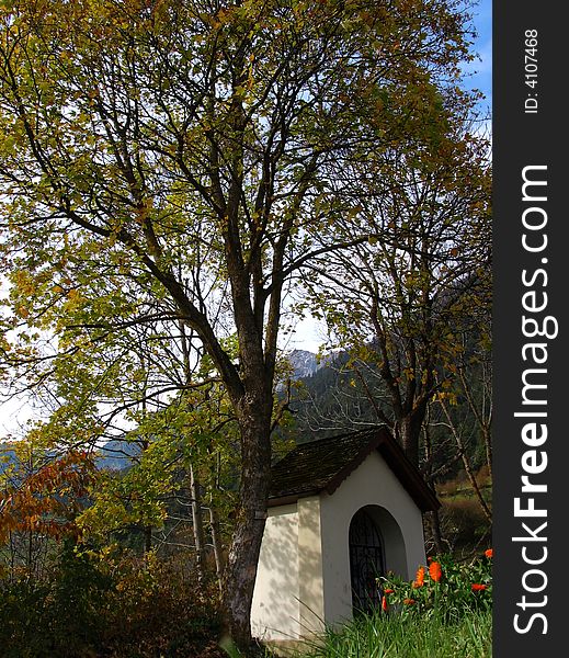 Scenic view of small chapel under trees with Alps mountains in background, Tirol, Austria. Scenic view of small chapel under trees with Alps mountains in background, Tirol, Austria.