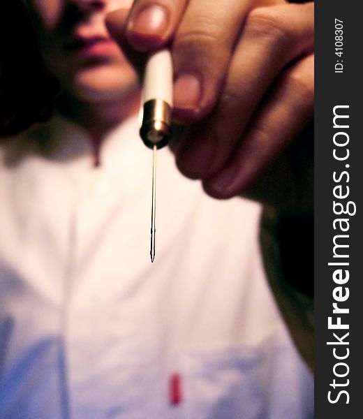 Scientist in the white coat in the background pointing histological needle to observer. Scientist in the white coat in the background pointing histological needle to observer