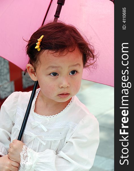 Cute beautiful Chinese young child under umbrella in summer