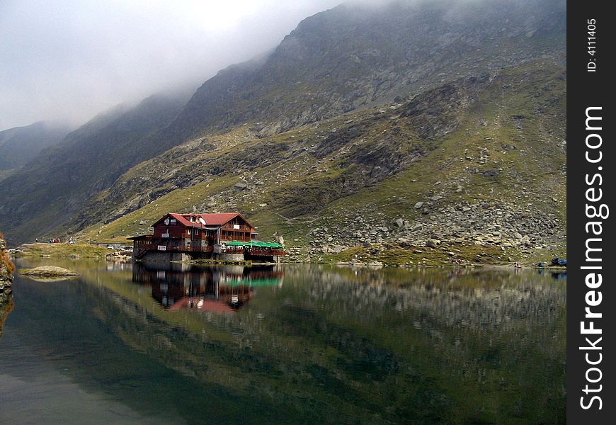 Lonely house built  on a glacier lake in the middle of the mountains, on a cloudy day. Lonely house built  on a glacier lake in the middle of the mountains, on a cloudy day.