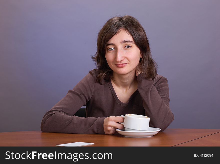 The beautiful girl with a coffee mug on a grey background. The beautiful girl with a coffee mug on a grey background