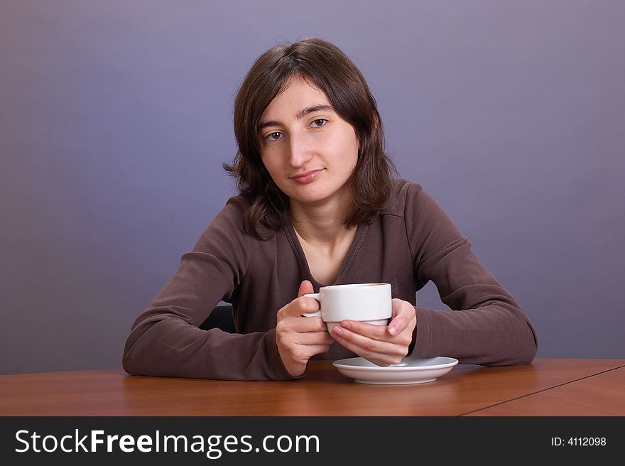The beautiful girl with a coffee mug on a grey background. The beautiful girl with a coffee mug on a grey background