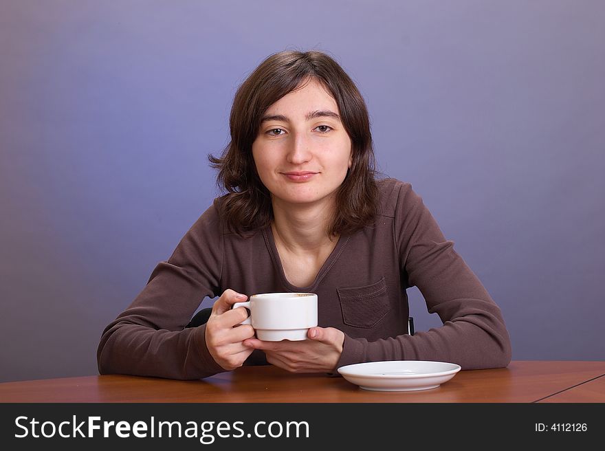 The beautiful girl with a coffee mug on a grey background. The beautiful girl with a coffee mug on a grey background