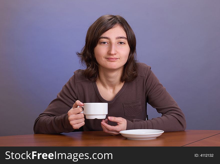 The beautiful girl with a coffee mug on a grey background. The beautiful girl with a coffee mug on a grey background