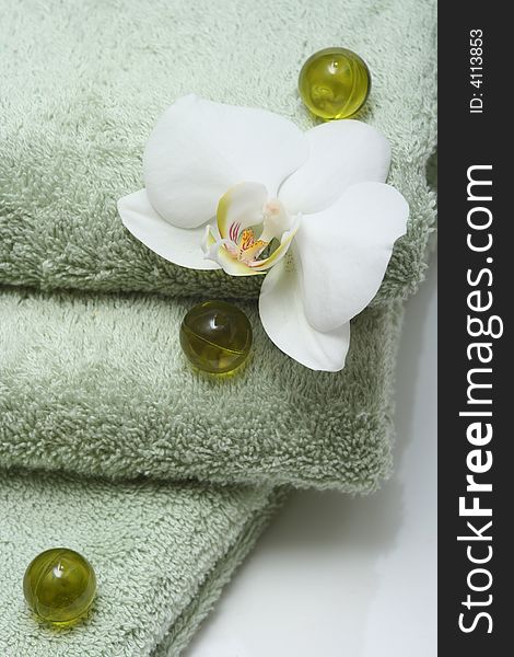 Bath oil pearls with orchid and green towels. Bath oil pearls with orchid and green towels.