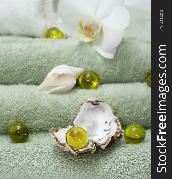 Bath oil pearls,shells on green towels. Bath oil pearls,shells on green towels.