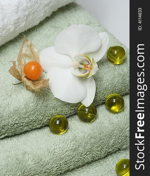 Bath oil pearls with orchid and green towels. Bath oil pearls with orchid and green towels.