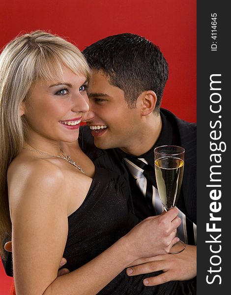 Young, hugging and smiling couple. Woman is holding glass of champagne. Young, hugging and smiling couple. Woman is holding glass of champagne