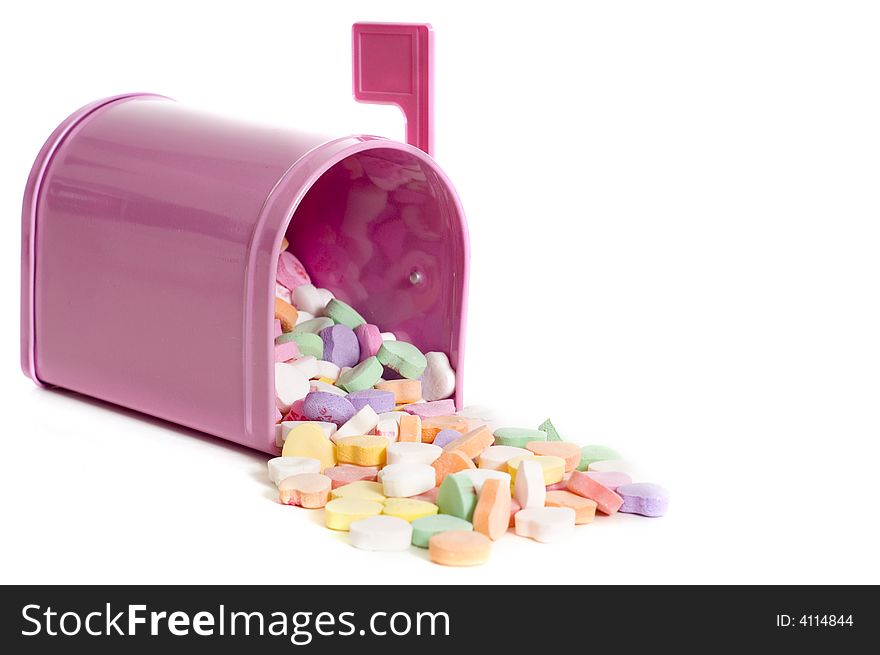 A pink mailbox overflowing with pastel colored conversation hearts on a white background with copy space. A pink mailbox overflowing with pastel colored conversation hearts on a white background with copy space