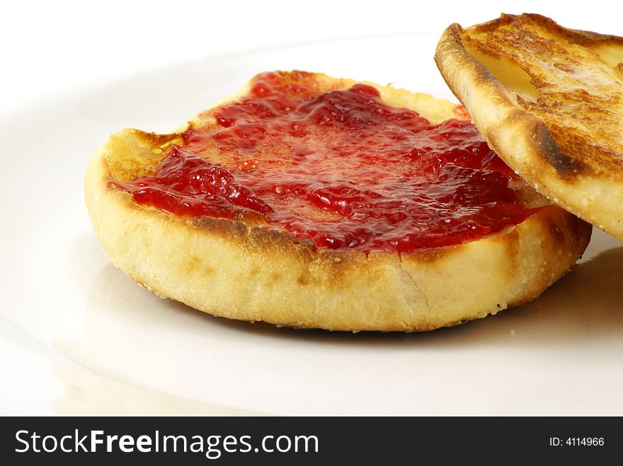 Lightly toasted sourdough english muffins with butter and strawberry preserves on white background.