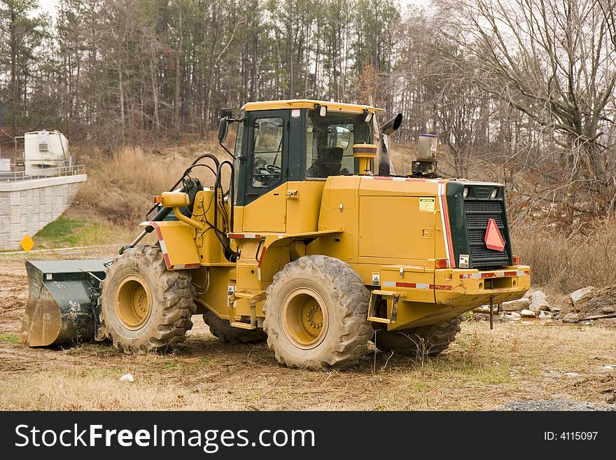 A large bulldozer on a construction site in the trees. A large bulldozer on a construction site in the trees