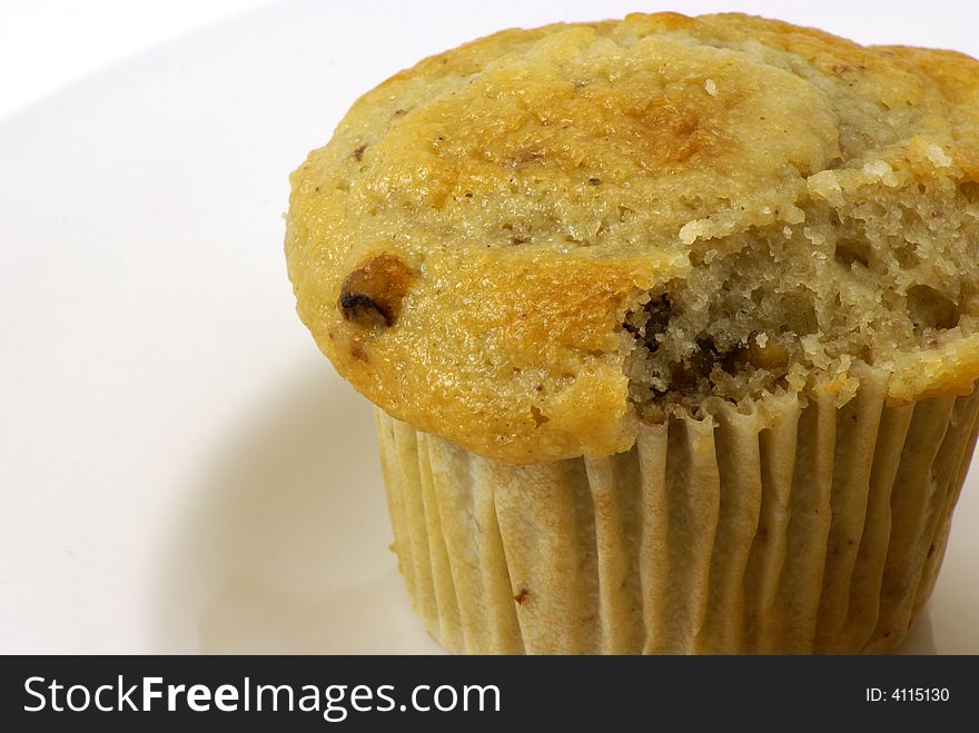 Fresh baked moist banana nut muffins on white plate and background.