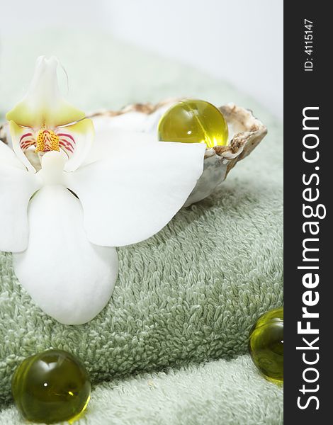 Olive oil bath pearls with orchid on green bath towels. Olive oil bath pearls with orchid on green bath towels.