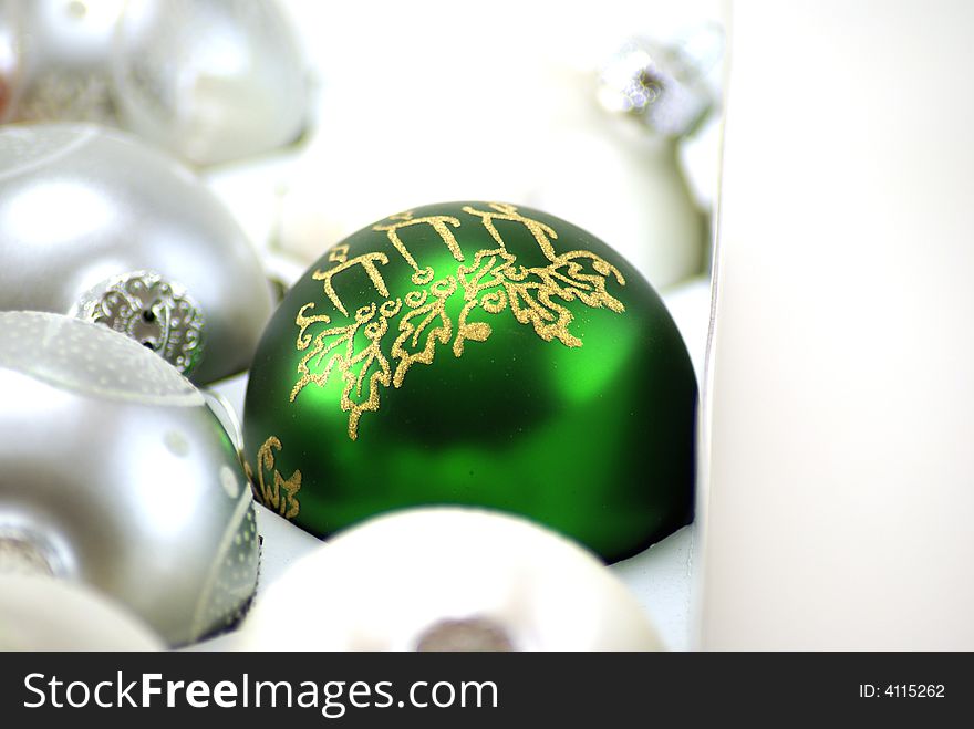 Shiny Green Christmas ornament still in the box, surounded by silver and white, waiting to be hung on the tree. Shiny Green Christmas ornament still in the box, surounded by silver and white, waiting to be hung on the tree.