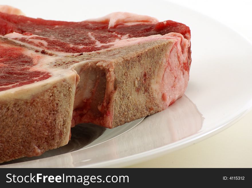 Very large and thick, fresh, juicy uncooked tbone steak on white plate with copy space. Very large and thick, fresh, juicy uncooked tbone steak on white plate with copy space.