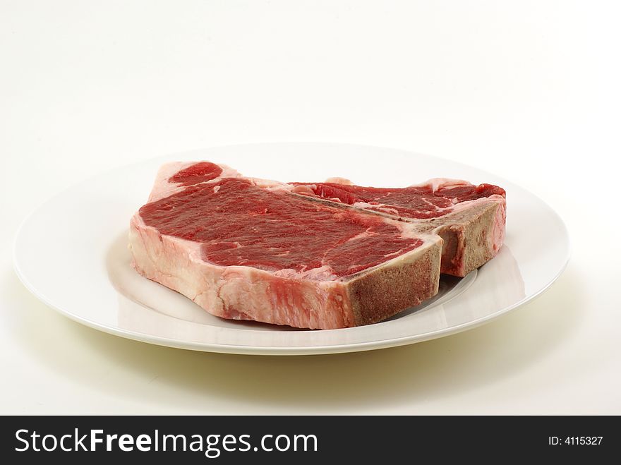 Very large and thick, fresh, juicy uncooked tbone steak on white plate with copy space. Very large and thick, fresh, juicy uncooked tbone steak on white plate with copy space.