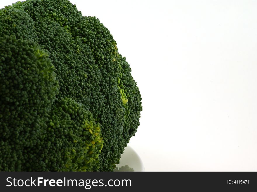 Large bunch of raw broccoli with leaves and stems on white plate.