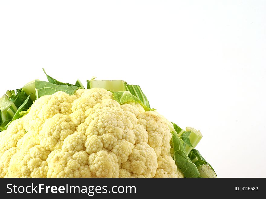 Close up of fresh raw cauliflower head surrounded by leaves.