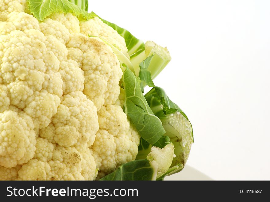 Close up of fresh raw cauliflower head surrounded by leaves.